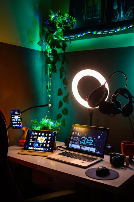 Vibrant gaming and workspace setup featuring laptop, tablet, smartphone, LED lights, and microphone.